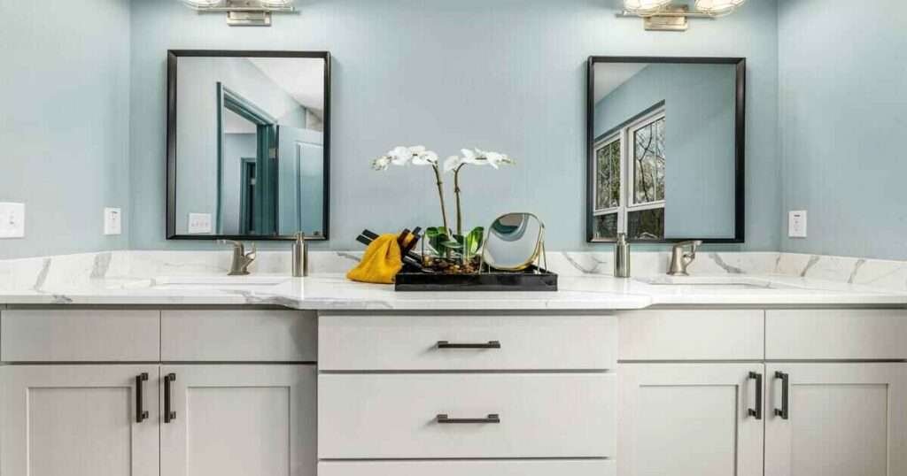 Modern bathroom vanity with a blue wall, white countertop, and two mirrors.
