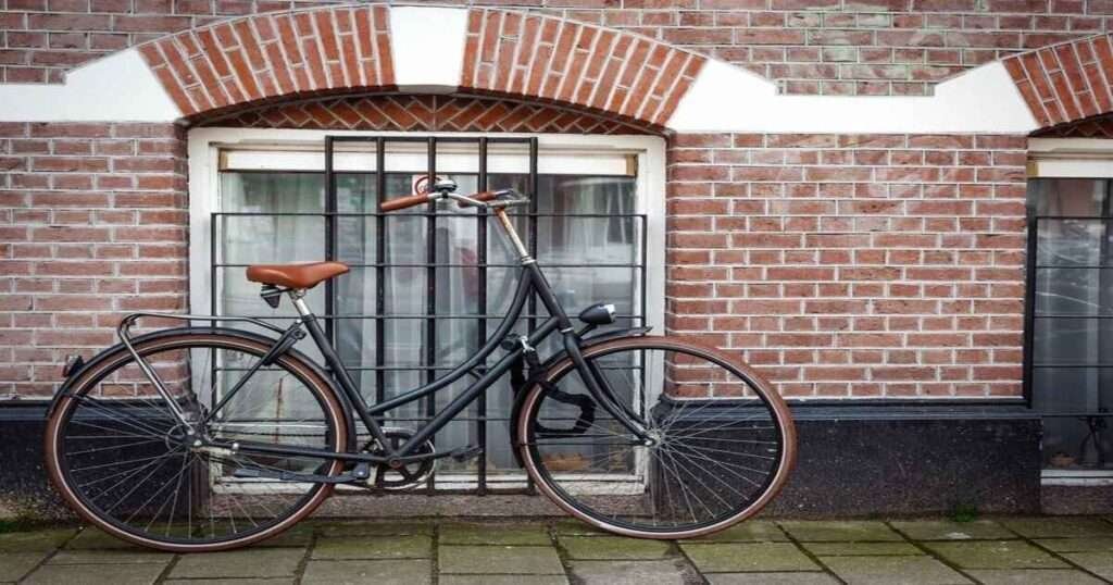 An adult bicycle standing in front of a wall 